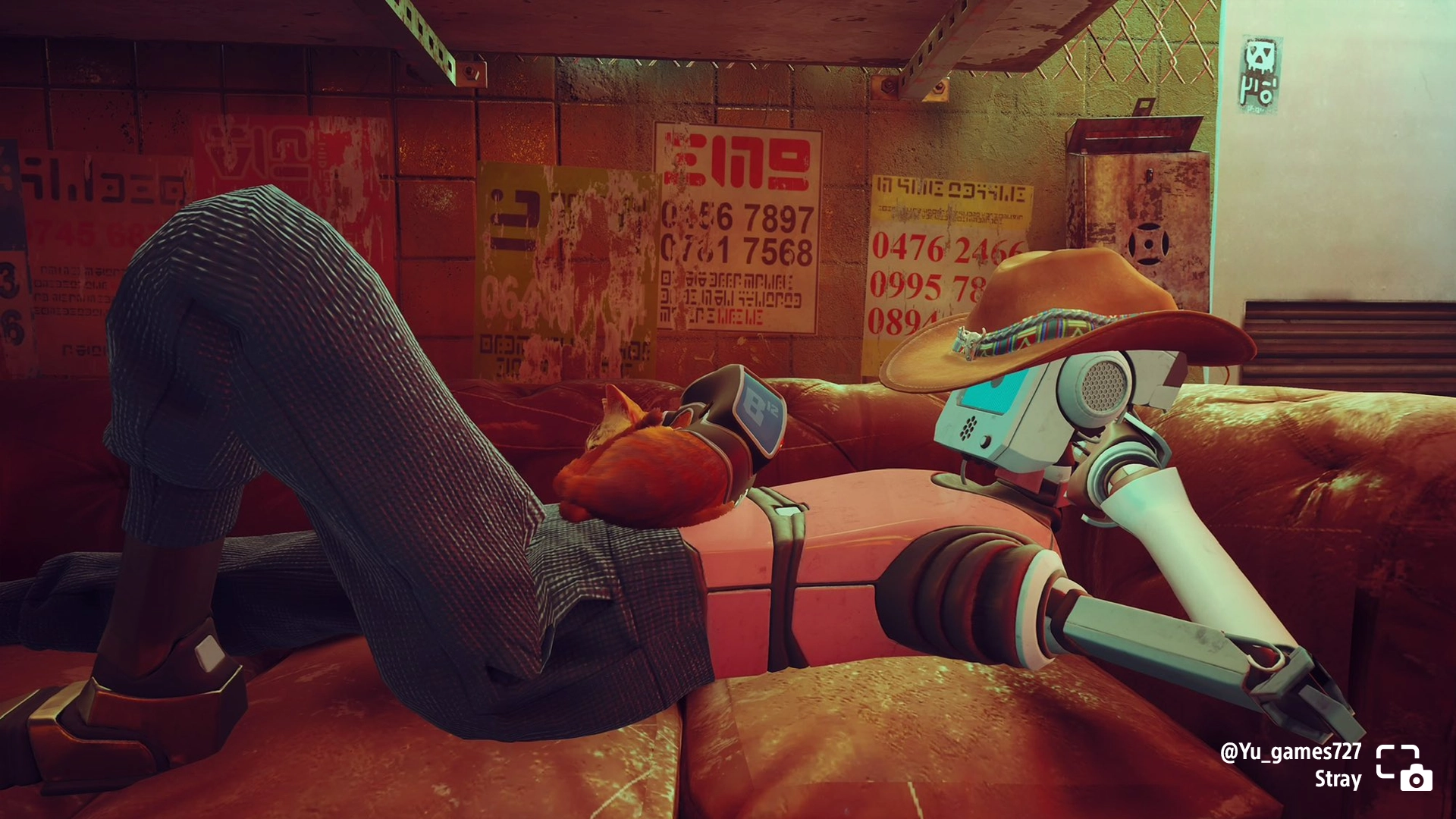 A robotic character relaxes on a couch with a cat in Stray, showcasing a cozy gaming moment. #PSshare #PSBlog