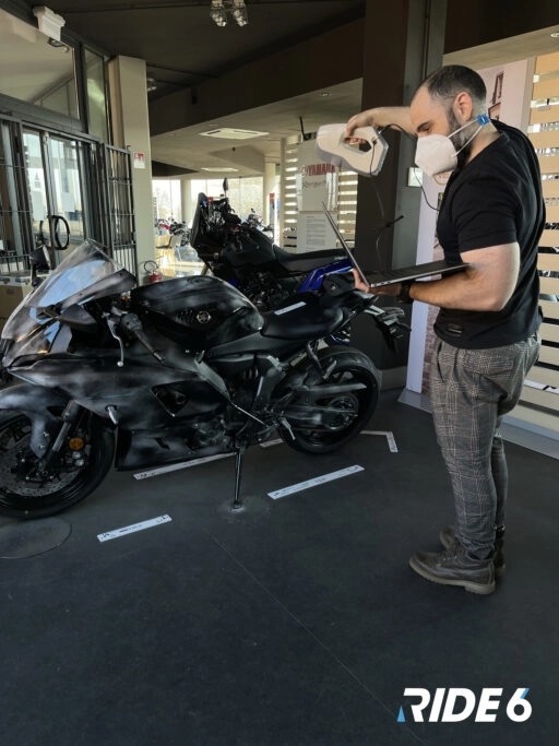 A developer scans a motorcycle for detailed 3D modeling in Ride 6, showcasing advanced gaming technology and realism.