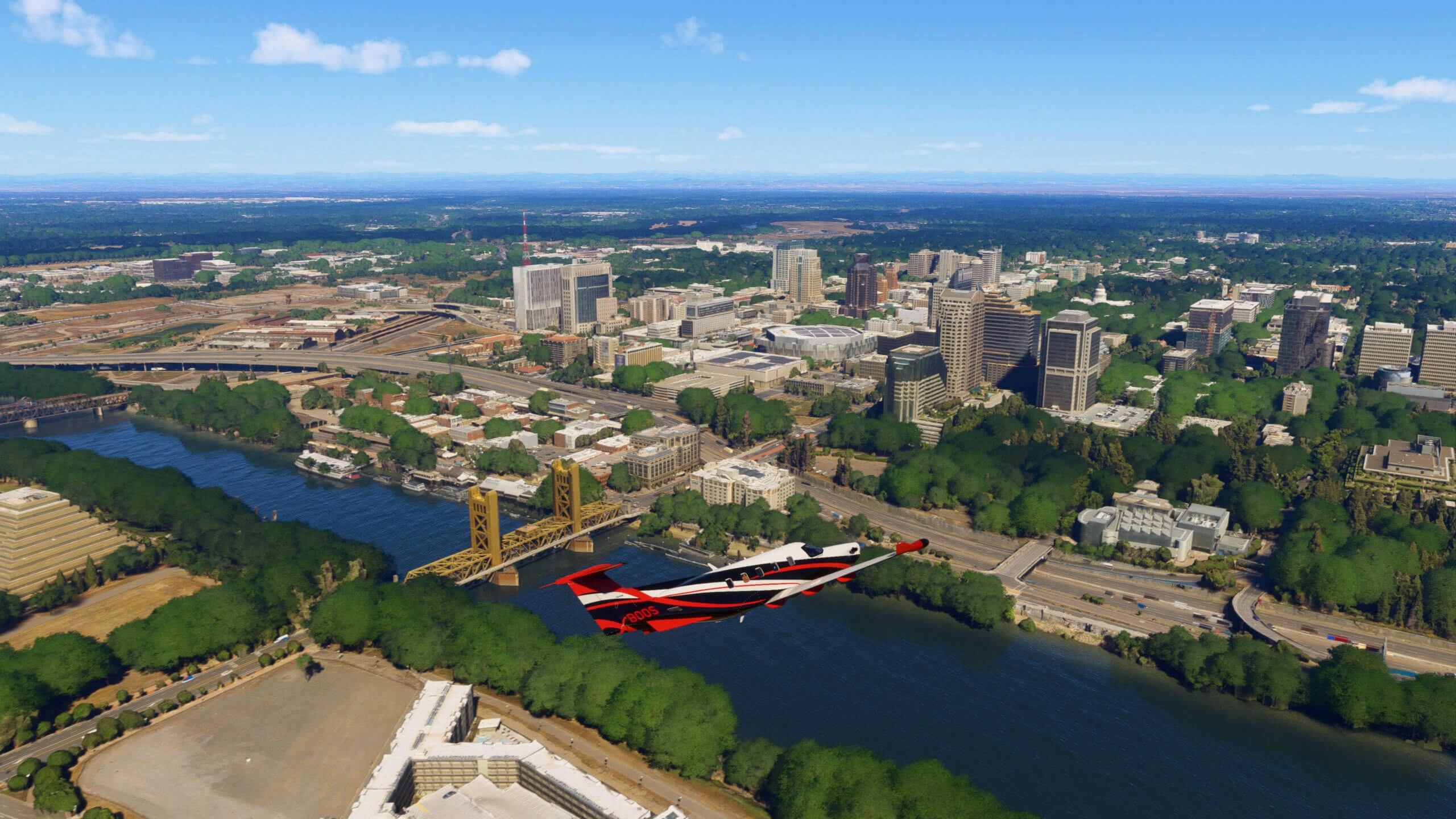 Aerial view of Sacramento with Tower Bridge, lush greenery, and urban skyline under a clear blue sky