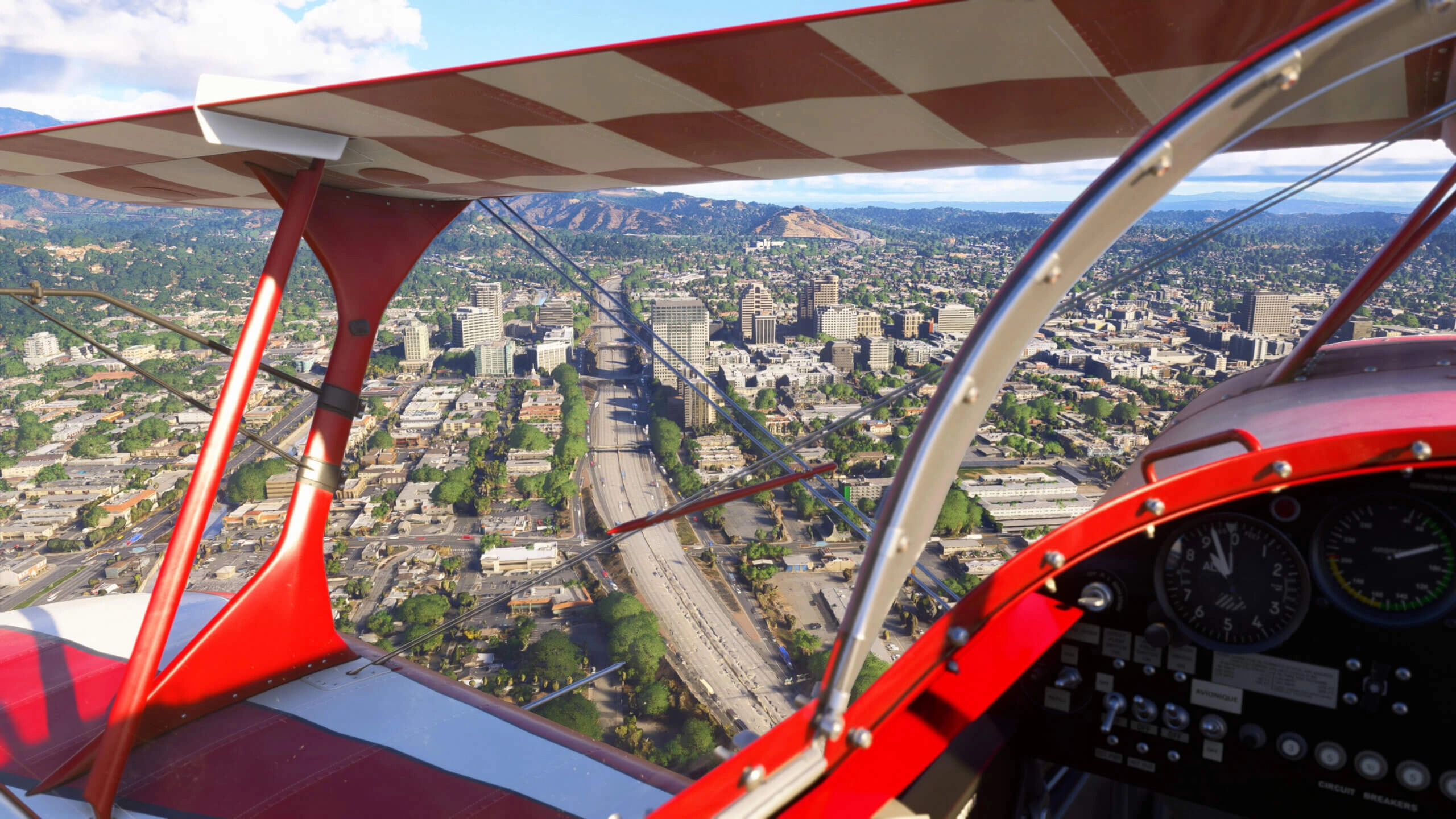 A biplane cockpit view of a detailed urban landscape in California, showcasing city buildings and roads