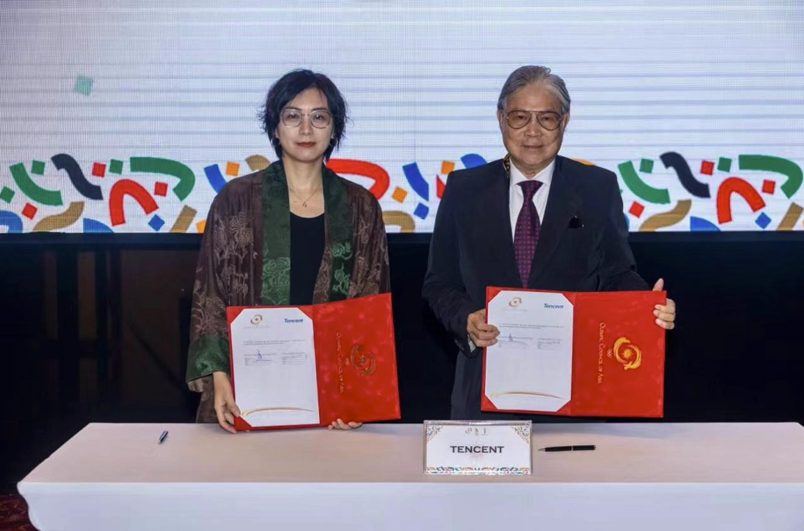 Tencent Esports and OCA representatives holding signed agreements at a partnership ceremony in Bahrain
