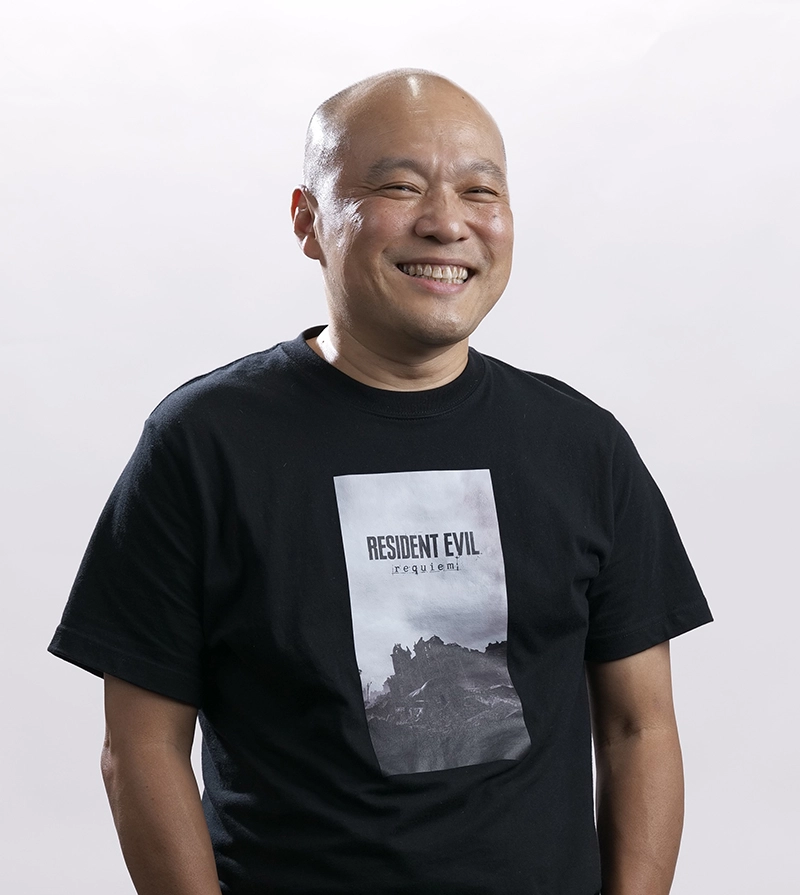 Man smiling, wearing a Resident Evil Requiem t-shirt, related to the latest game launch on PS5