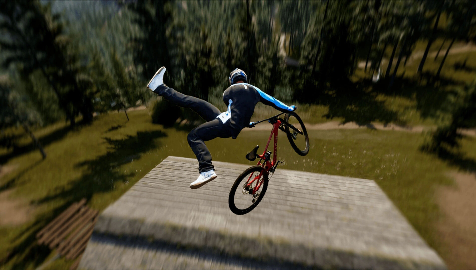Mountain biker performing a trick mid-air on a red bike, surrounded by a lush forest landscape