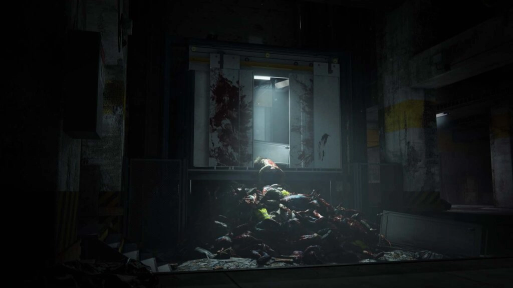A dark, eerie room with a pile of zombie bodies illuminated by a faint light from an open elevator shaft