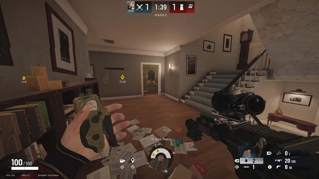First-person view in Rainbow Six Siege, player holding a gadget, aiming in a room with scattered papers