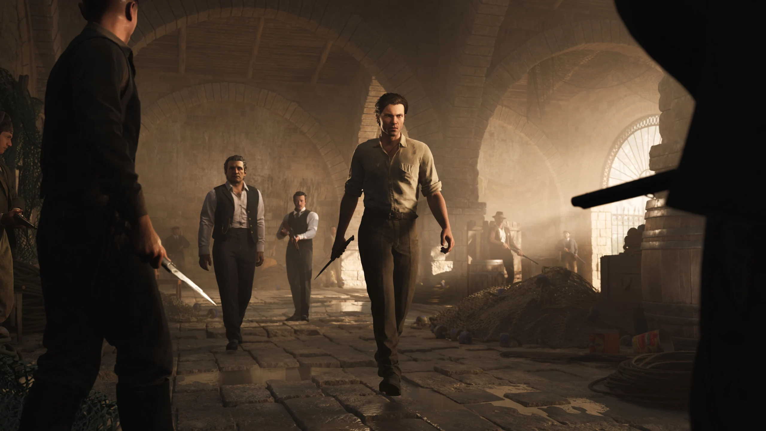 Men in vintage attire walk through a dimly lit, arched stone cellar, holding weapons, exuding tension