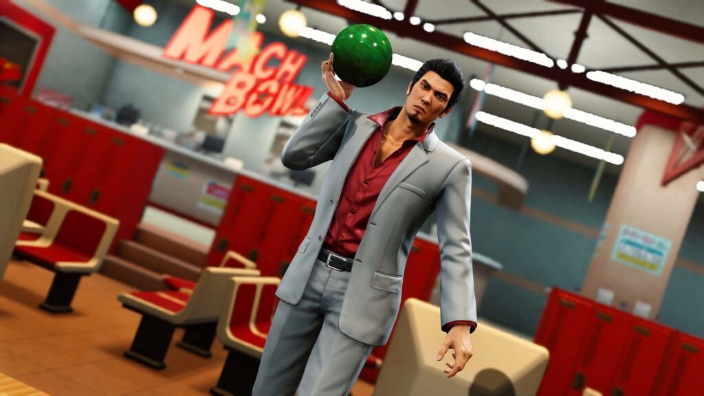 Kiryu in a bowling alley holding a green bowling ball, wearing a gray suit with a red shirt, ready to play