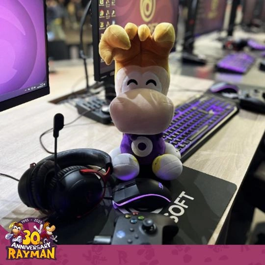 Rayman plush toy on a gaming desk with headset and controller, celebrating 30th anniversary event