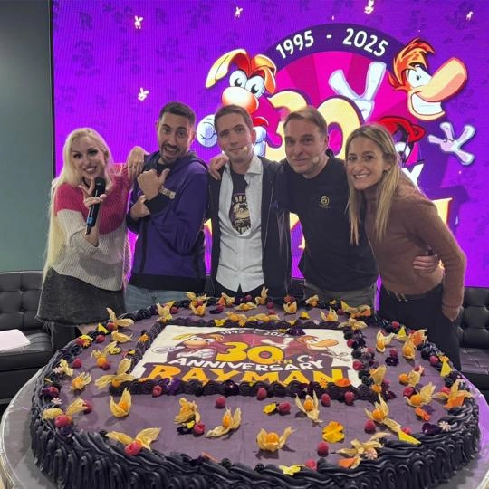 Rayman team members celebrate 30th anniversary with a large themed cake at a gaming event